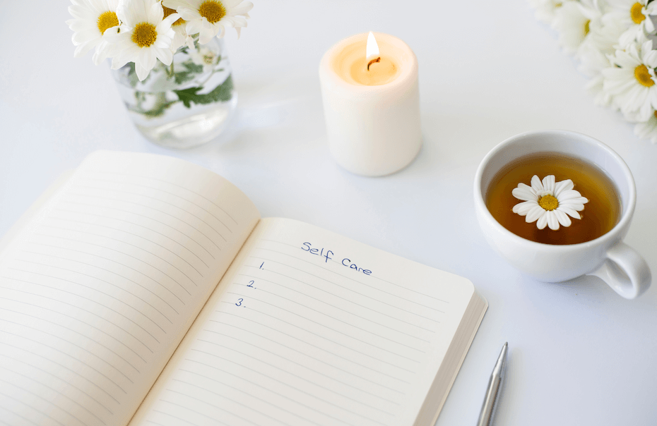 Cosy journaling scene with an open self-care journal on a white table top.